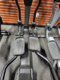 Side view of the rear-drive flywheel housing and oversized non-slip foot pedals on a Life Fitness Elevation Series 95X commercial elliptical trainer.